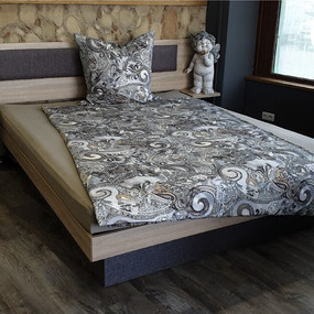 Modernes Boxspringbett mit gemusterter Bettwäsche und Holzrahmen im Schlafzimmer.