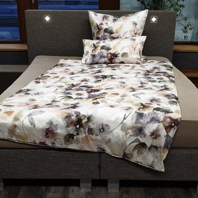 Modernes Boxspringbett mit floral gemusterter Bettwäsche und Kissen im Schlafzimmer.