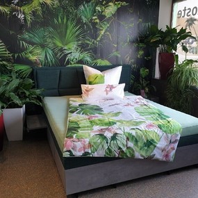 Modernes Boxspringbett mit tropischer Bettwäsche und vielen Zimmerpflanzen im Schlafzimmer.